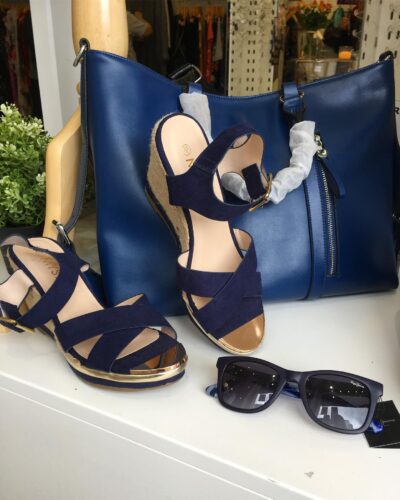 a paif of dark blue high shoes and a beautiful blue letter purse and a sungless