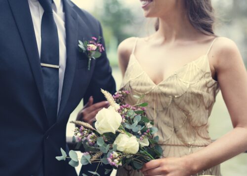 Photo of a couple, the women is holding a bouquet and the man is wearing a suit