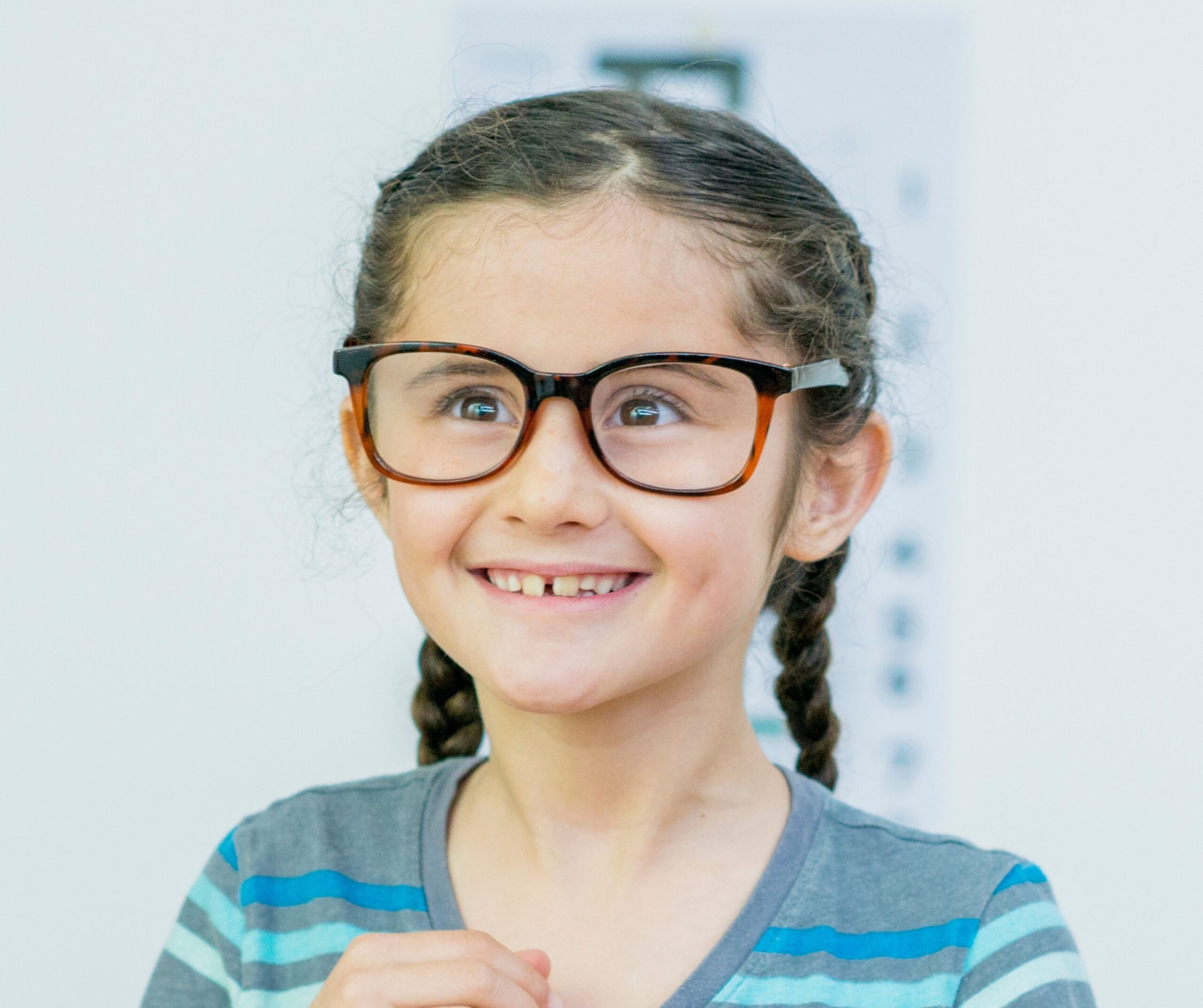 girl ooking excited aged about 10, wearing a pair of glasses, with braided and a blue top on