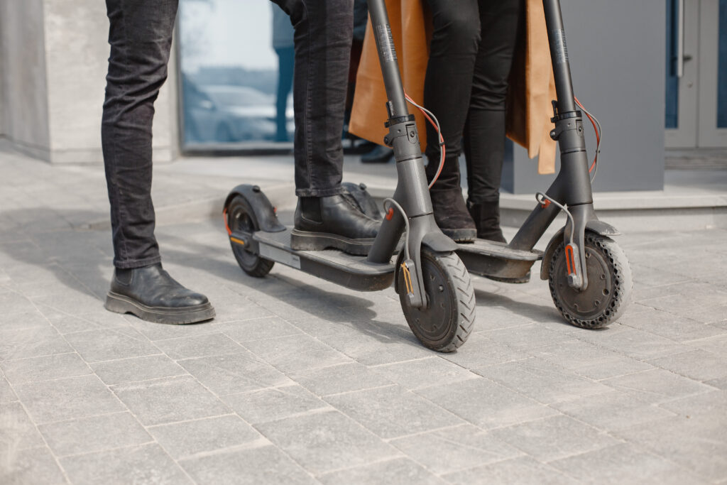 Close up on two people's legs as they stand on their e-scooters