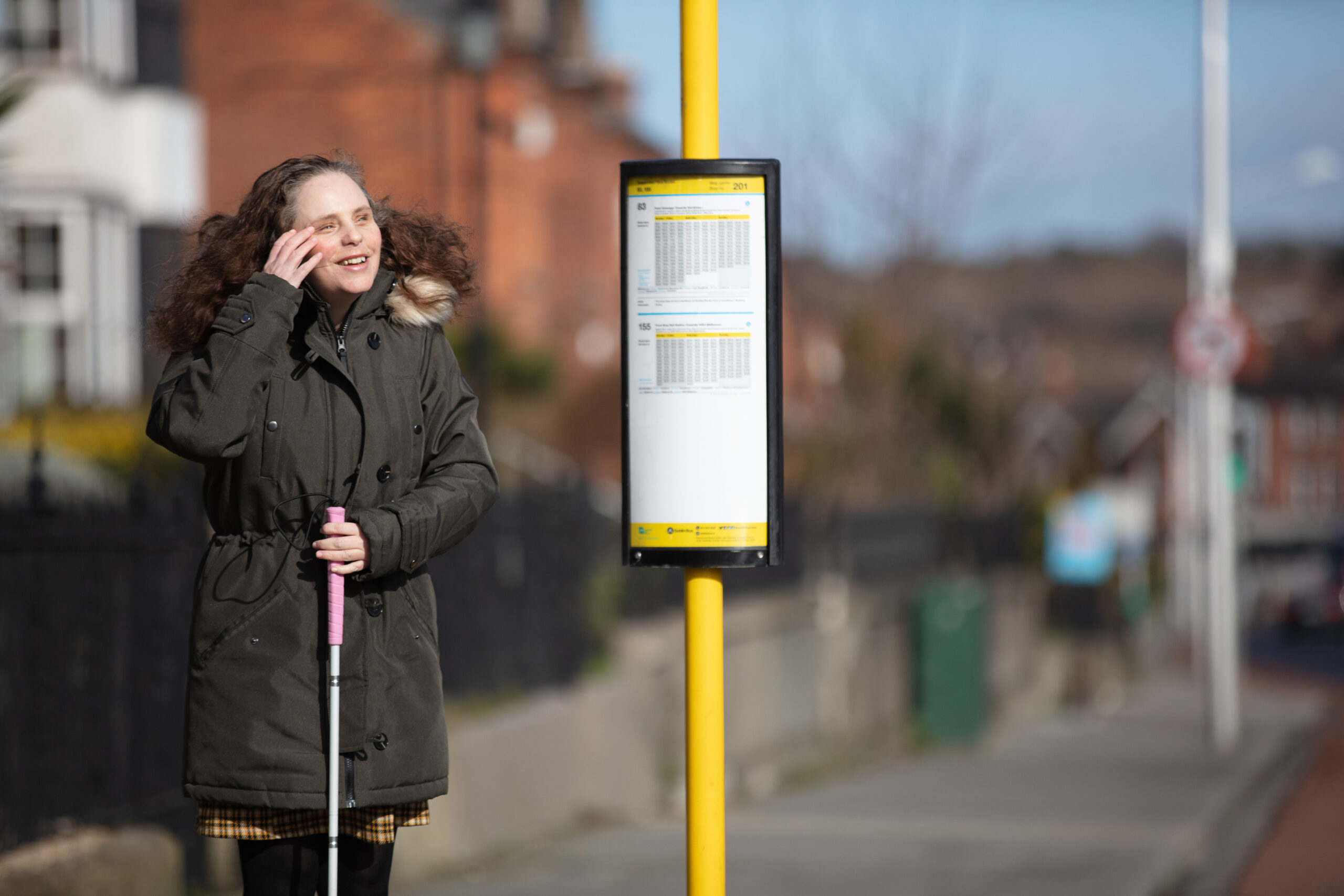 An NCBI service user standing at a bus stop waiting for a bus to come