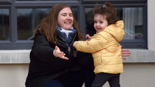 Jade McCormack crouches down with her arms held wide as her daughter Sadhbh runs toward her to give her a hug