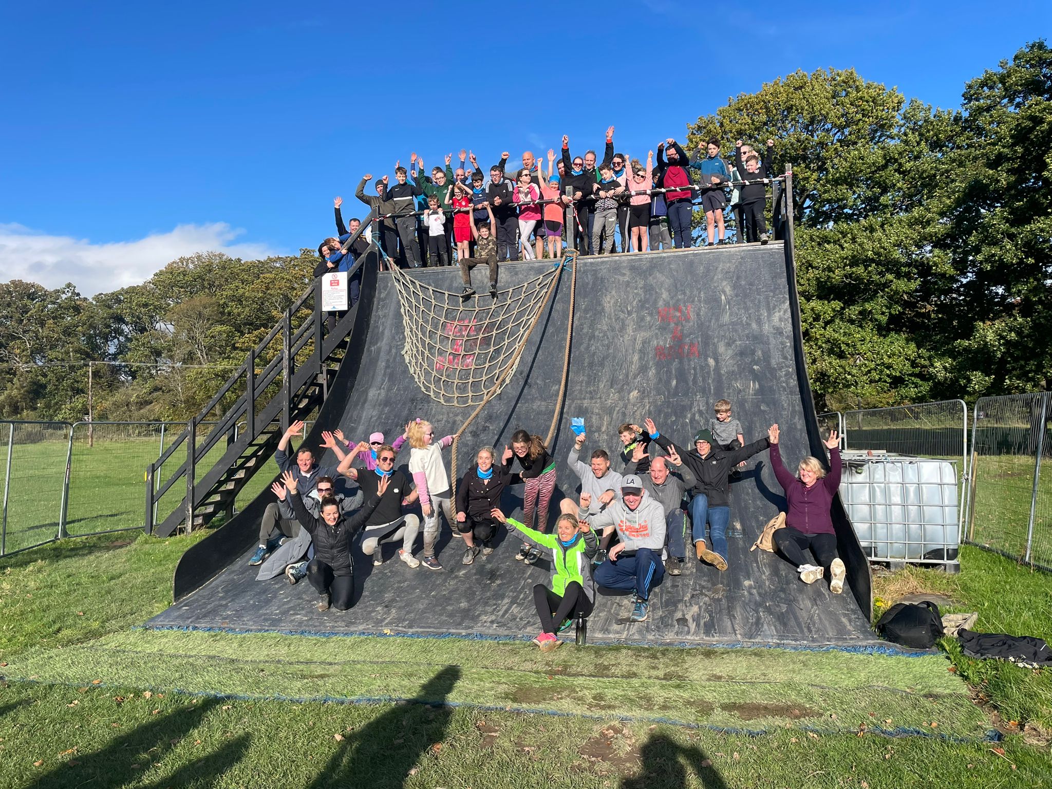 The entire group who took part in the Ireland's Fittest Family event pose for a picture as some members stand on the top of a ramp used in the obstacle course, while others sit at the bottom of the ramp.