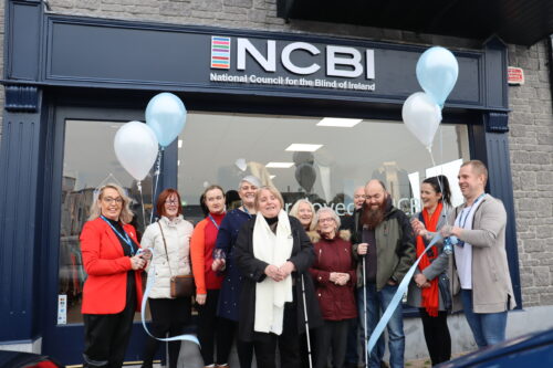 A group standing outside the NCBI Portarlington store. Among the group are service users, including Marian Murray who was the VIP guest to cut the ribbon to open the store.
