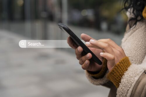 Woman holding a smartphone next to an image of a search bar